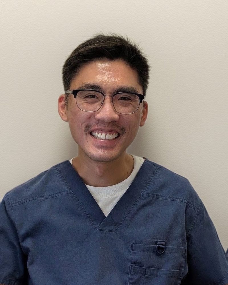Dr. Nicholas Warounthorn, smiling, in navy scrubs